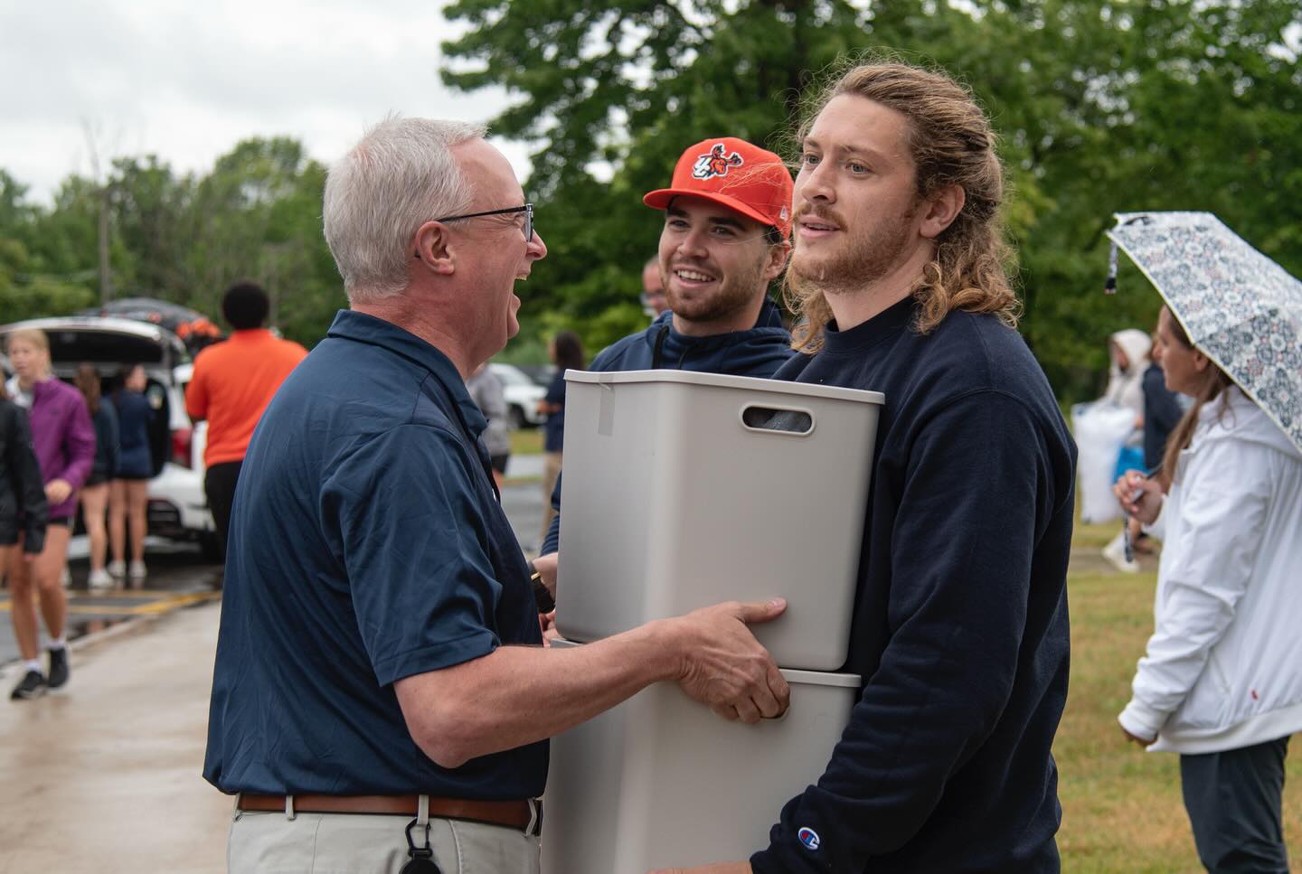 President Todd Pfannestiel helps students with plastic bins during move-in day.