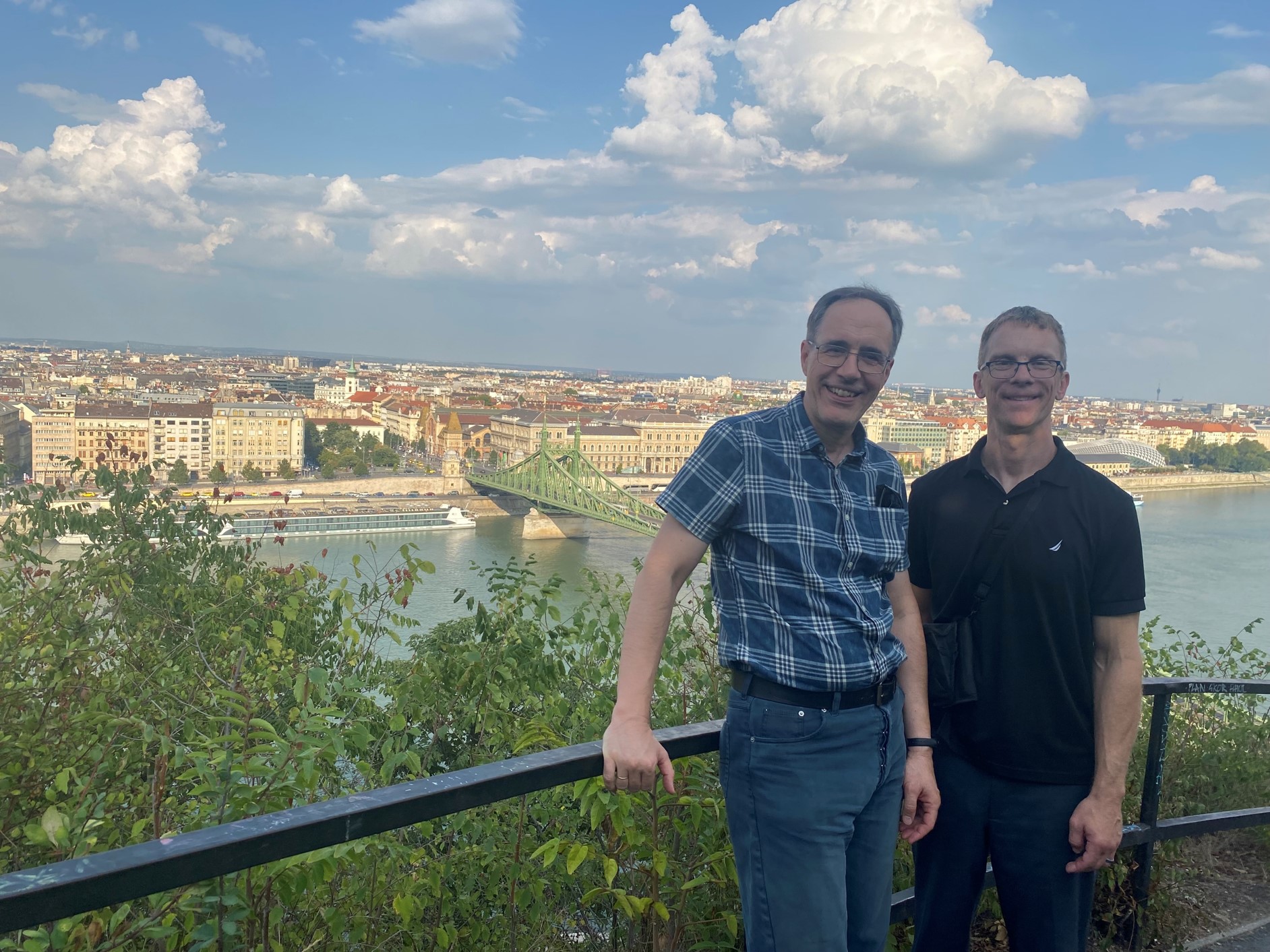 Luke Perry and Faculty Host Dr Karoly Pinter in Budapest, with water and buildings behind them.